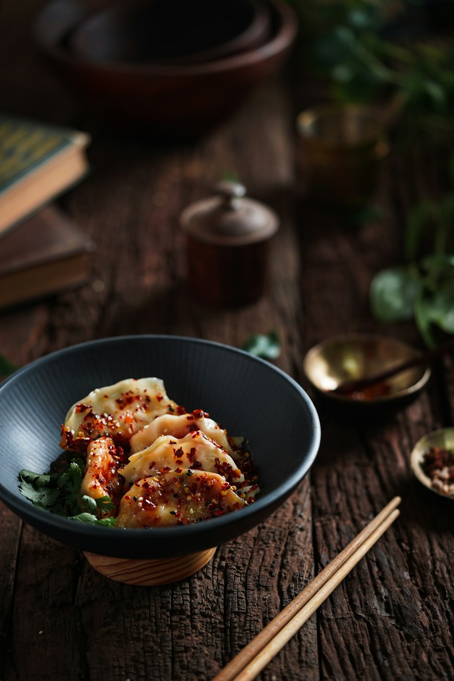 Dumplings in a dark bowl, covered in chilli flakes and oil